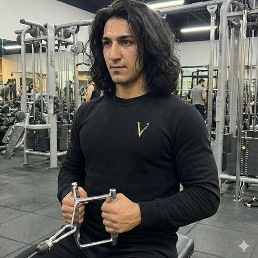 Man in a gym holding a weight machine, wearing a Vici Logo Crewneck