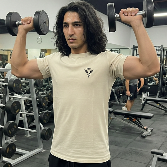 Man lifting dumbbells in a gym setting wearing the bone color Vici Logo Shirt